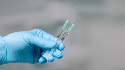 This image is a photo of a gloved hand holding two syringes