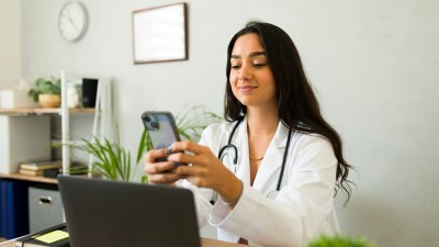 Ärztin scrollt am Smartphone