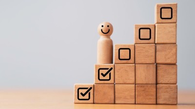 Smiling toy figure on stairs made of wooden blocks