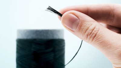 Zwei Finger halten dünne schwarze Fasern.