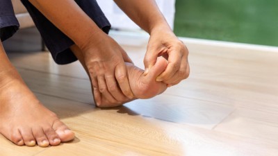 Frau hält sich den linken Fuß