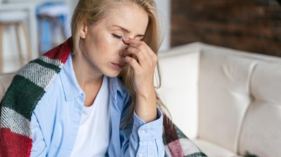 Frau mit Schmerzen sitzt auf dem Sofa