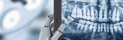 Roboterhand hält zahnmedizinisches Röntgenbild vor dem Hintergrund einer Behandlungsleuchte