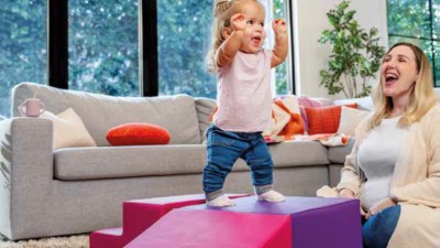 Kind streckt sich freudig, Mutter sitzt und lacht