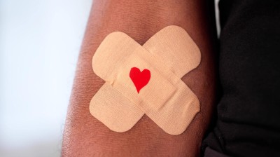 Kreuzweise geklebte Pflaster auf Haut mit aufgemaltem Herz