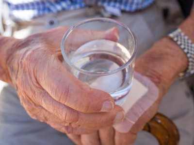 Alte Person hält Wasserglas in der Hand