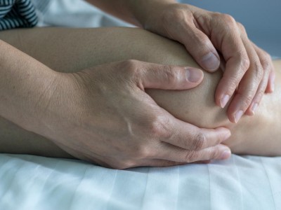 Frau unkenntlich fasst sich ans Knie