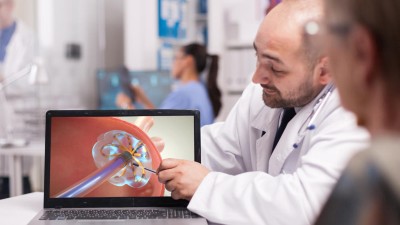 Arzt erklärt Patient Operation am Laptop