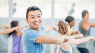 This image is a photo of a Zumba class with a young man in foreground