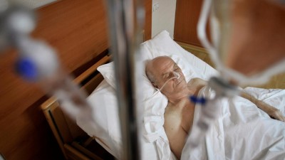 Älterer Mann im Krankenhausbett hinter Infusionsständer