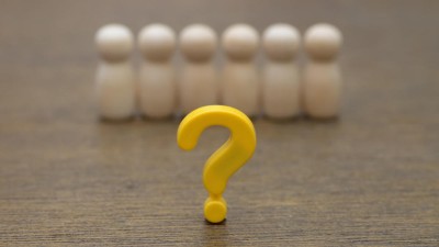 Yellow question mark in front of a row of wooden figures