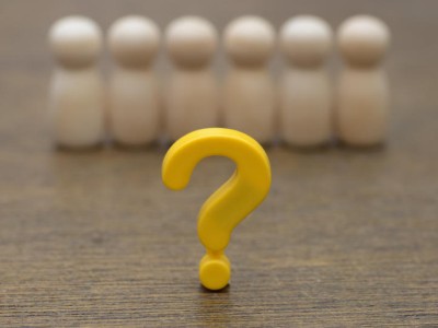 Yellow question mark in front of a row of wooden figures