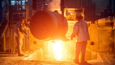 Zwei Arbeiter kippen flüssigen Stahl aus. 