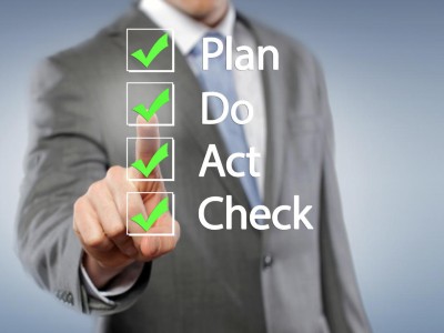 Ein Mann zeigt auf eine Checkliste mit Plan, Do, Act, Check