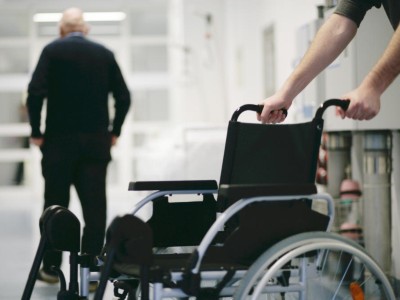 Senior und Rollstuhl auf Flur