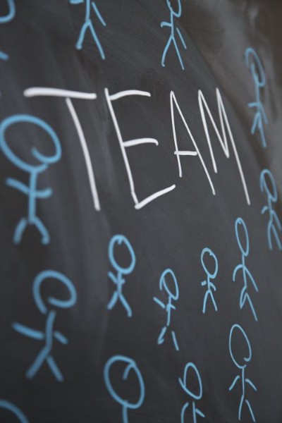 Team und blaue Strichmännchen an der Tafel.