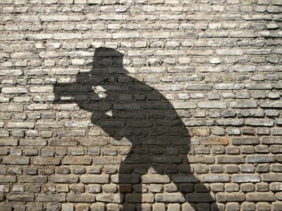 Schatten eines Mannes mit Hut und Kamera an der Wand