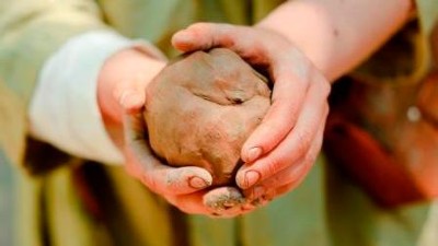 Zwei Hände halten ein Lehmkugel