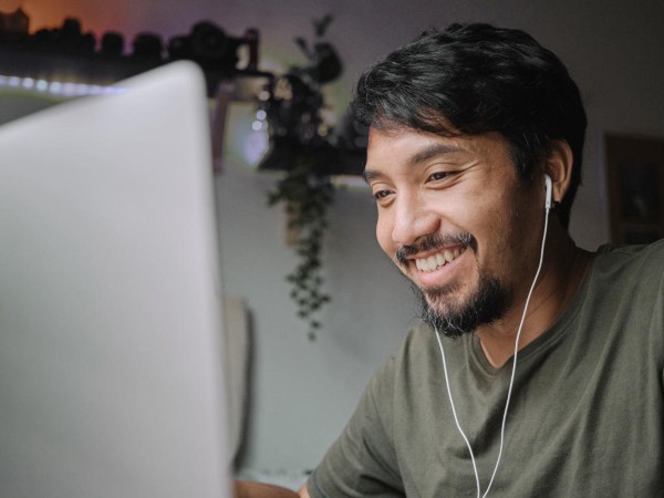 Young, smiling man uses desktop computer