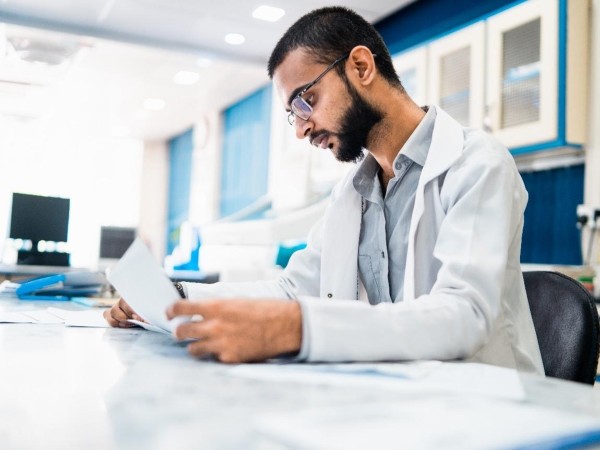 A young male scientist sitting at a desk working and reviewing a paper