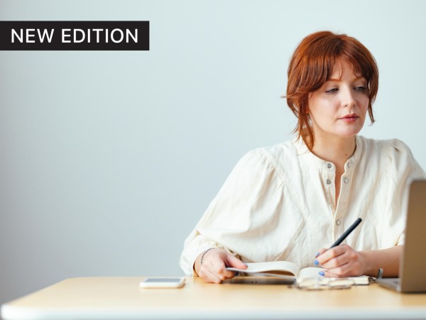 Femals researcher sitting at a desk with a pen and notebook looking at a laptop