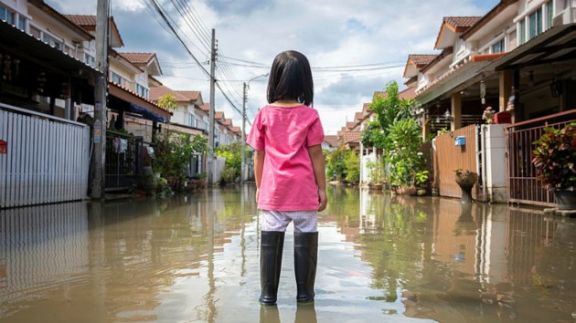 A girl watching a flood on a village road