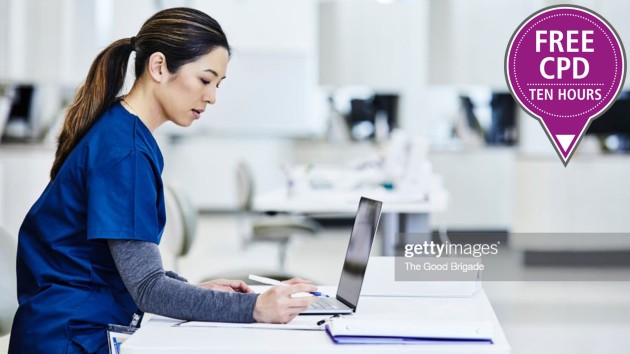 Woman in scrubs working on a laptop