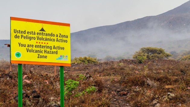 Image shows a roadside sign at Telica volcano (Nicaragua) saying “You are entering Active Volcanic Hazard Zone” in English and Spanish.