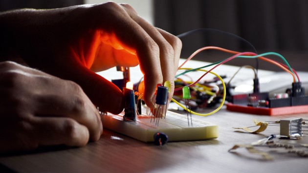 Light caught under the hand of a student as they plug wires into an electrical circuit