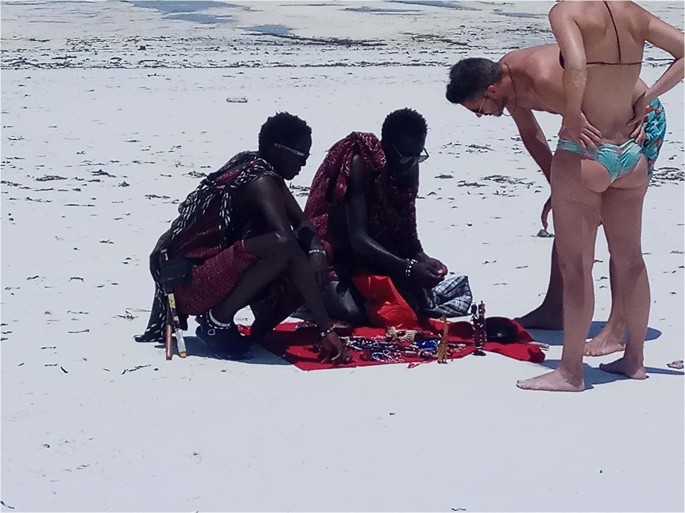 Topless ladies surrounded by dressed men at the beach