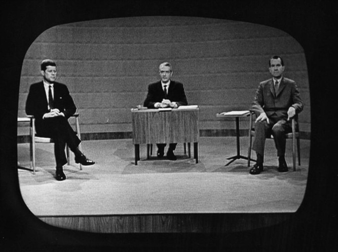 A television debate with three people, a host in the middle, and presidents Nixon and Kennedy.