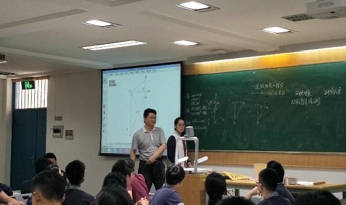 A photograph of a classroom with a teacher and students.