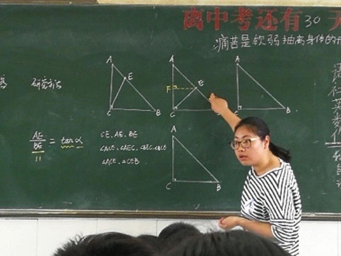 A photograph of a teacher teaching triangles on the board in a classroom.