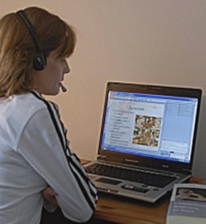 A photograph of a female student sitting and attending a meeting in a virtual classroom using the videoconferencing platform, Adobe Connect.