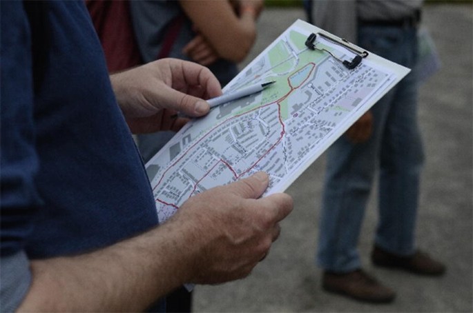 A photo of a person holding a notepad with a street map and a pen.