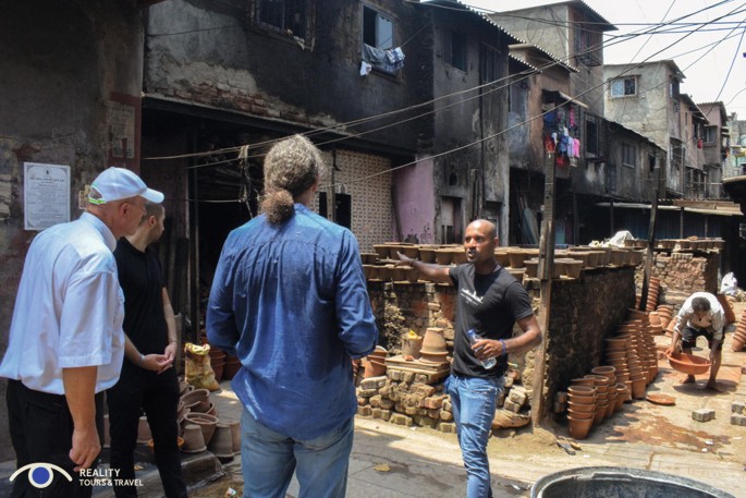 A photograph depicts a few tourists in Dharavi in Mumbai.