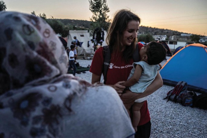 The photograph of the person who is carrying a small kid in her hand with a smile.