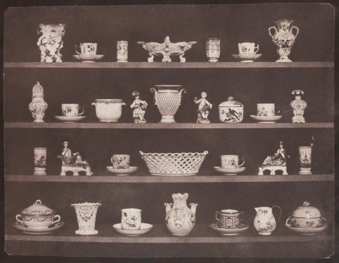 A photograph represents coffee cups, saucers, bowls, and idols arranged in rows.