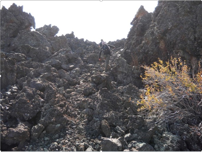 A lady climbs over a rocky terrain.