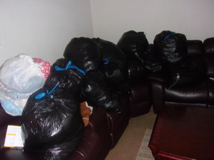 A photograph in which a person's belongings are bundled in plastic garbage bags tied with blue ties.