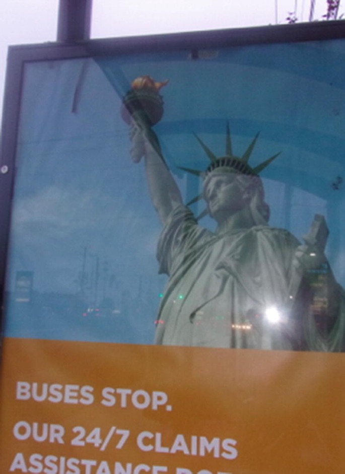 A photograph of a poster with the statue of liberty and "Buses Stop" written below it.