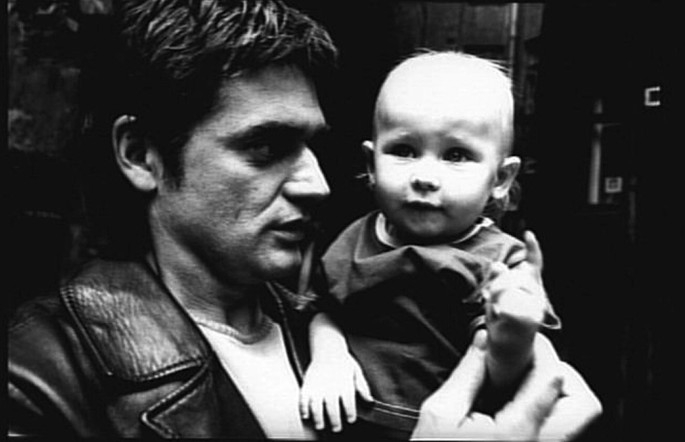 A screen capture from the movie, The Return. The father is looking at and holding a baby, the younger brother, Vanya.
