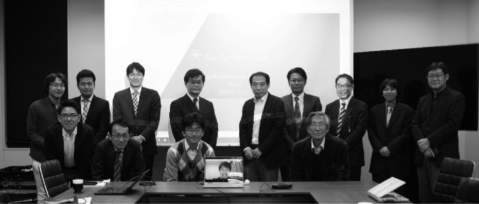 In a black and white group photograph of the fourteen members of the study group, one is on a computer screen, that convened on airborne ultrasound exposure.