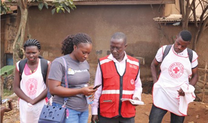 A group of young mappers and Red Cross volunteers gather field data.