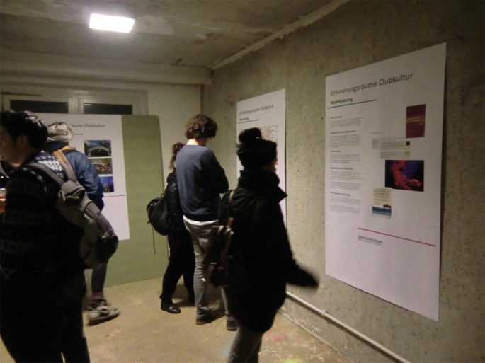 A picture captures people reading posters hung on the wall.