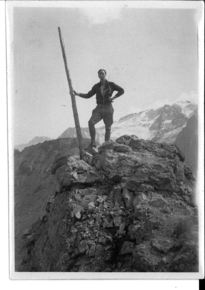 A photograph of Pawsey standing on a raised, rocky platform holding a pole.