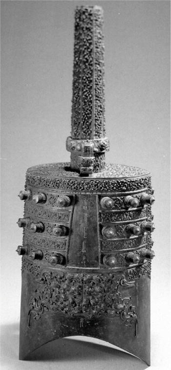 A photograph of a musical instrument, the Yong-bell. It has an arch-shaped bottom, straight sides on the cylindrical surface, and a columnar shank at the top.