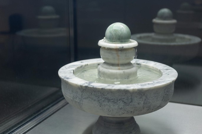 A photograph depicts a marble sphere water fountain. The installation is called The Alchemy, and has been installed in 2019.