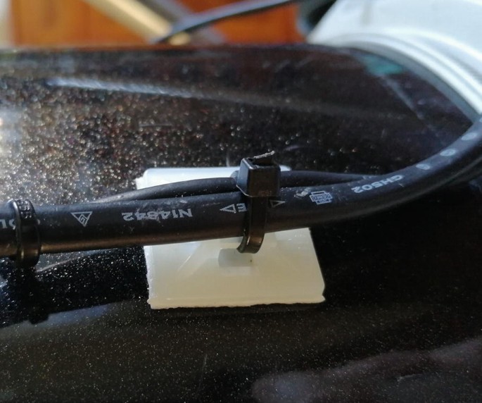 A photograph of a self-adhesive pad and plastic tie wrap, which is used to secure the cables to a telescope tube.