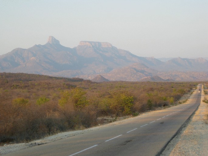 A photograph. A two-way road, dense thickets are grown below the granite domes.